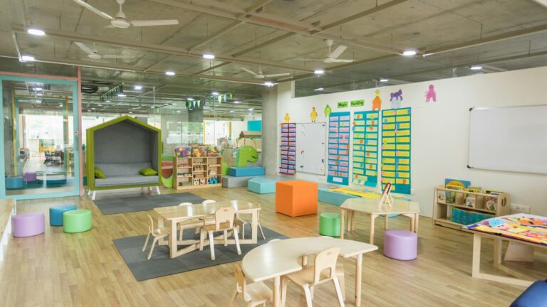 Bright day care classroom with child-sized tables, chairs, and learning displays.
