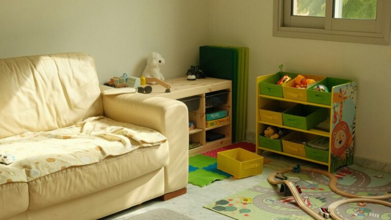Home living room set up as a play area with toy storage bins and a play mat.