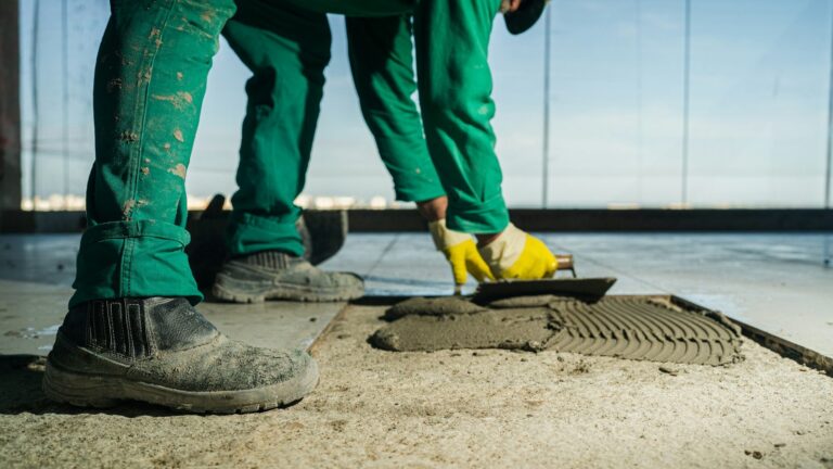 Two flooring installers spreading mortar on a floor at a jobsite.